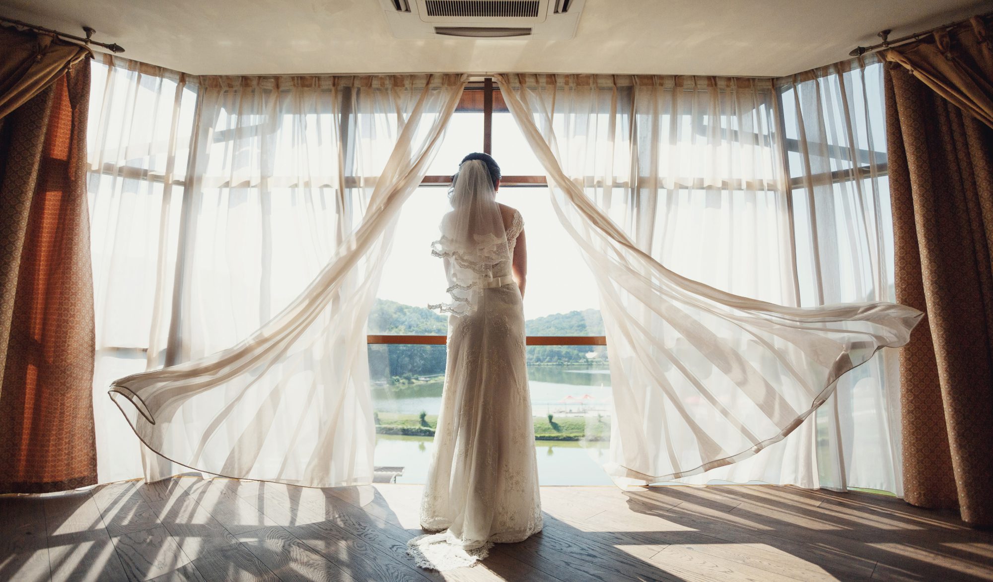 bride stands before panoramic window